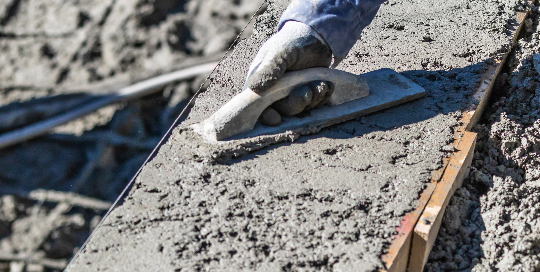 A photo of a concrete contractor smoothing recently poured concrete